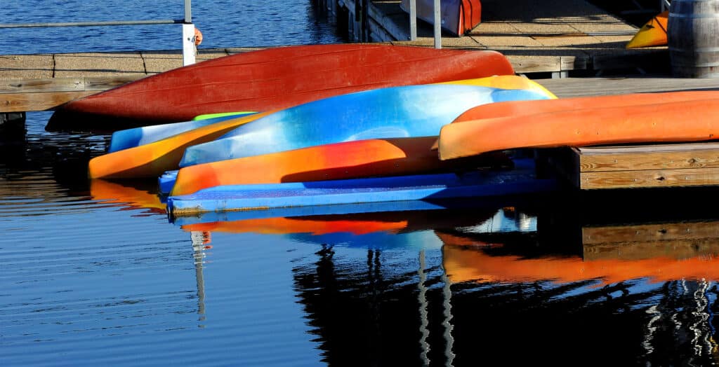 Vivid And Colorful Canoes Lay Upside Down At The Marina At Table